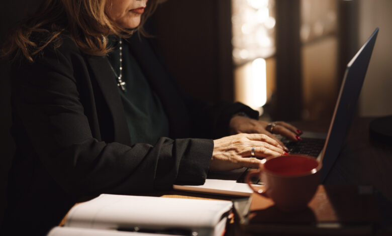 A businesswoman typing on a laptop at her home office desk