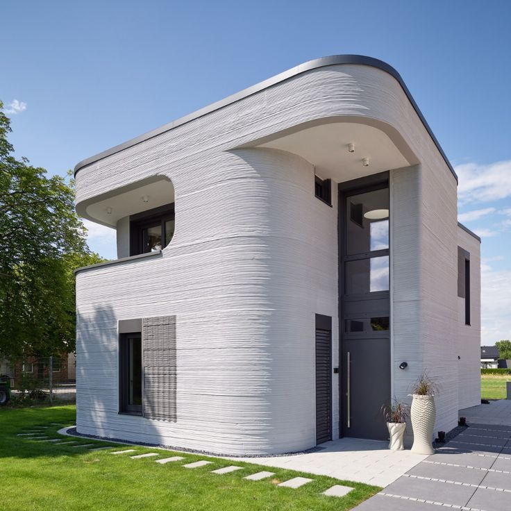 Finished 3D printed house with curved white walls and visible printed layers